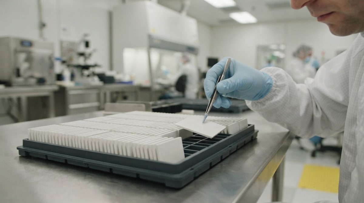 Engineer handling blank ceramic substrates with vacuum tweezers in a cleanroom