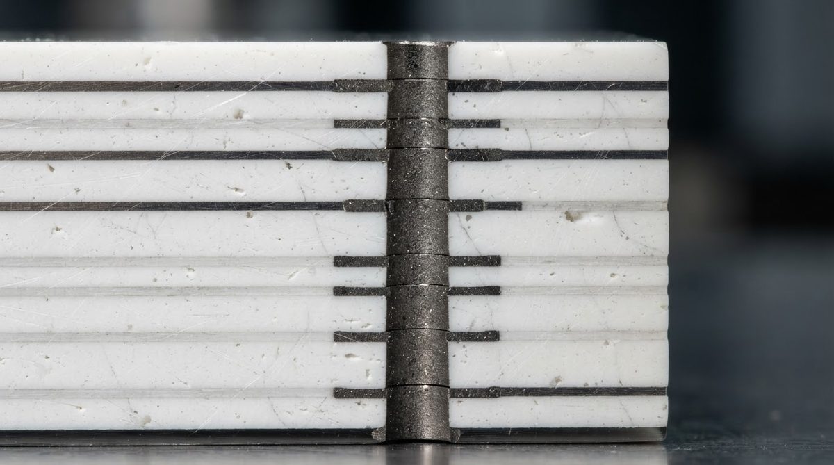 Cross-section of a fired HTCC substrate revealing internal tungsten vias and conductor layers