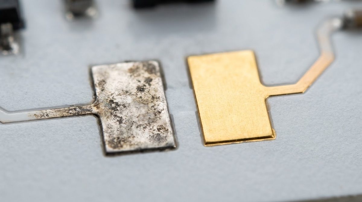 Close-up comparison of tarnished silver pad and clean gold pad on a ceramic substrate